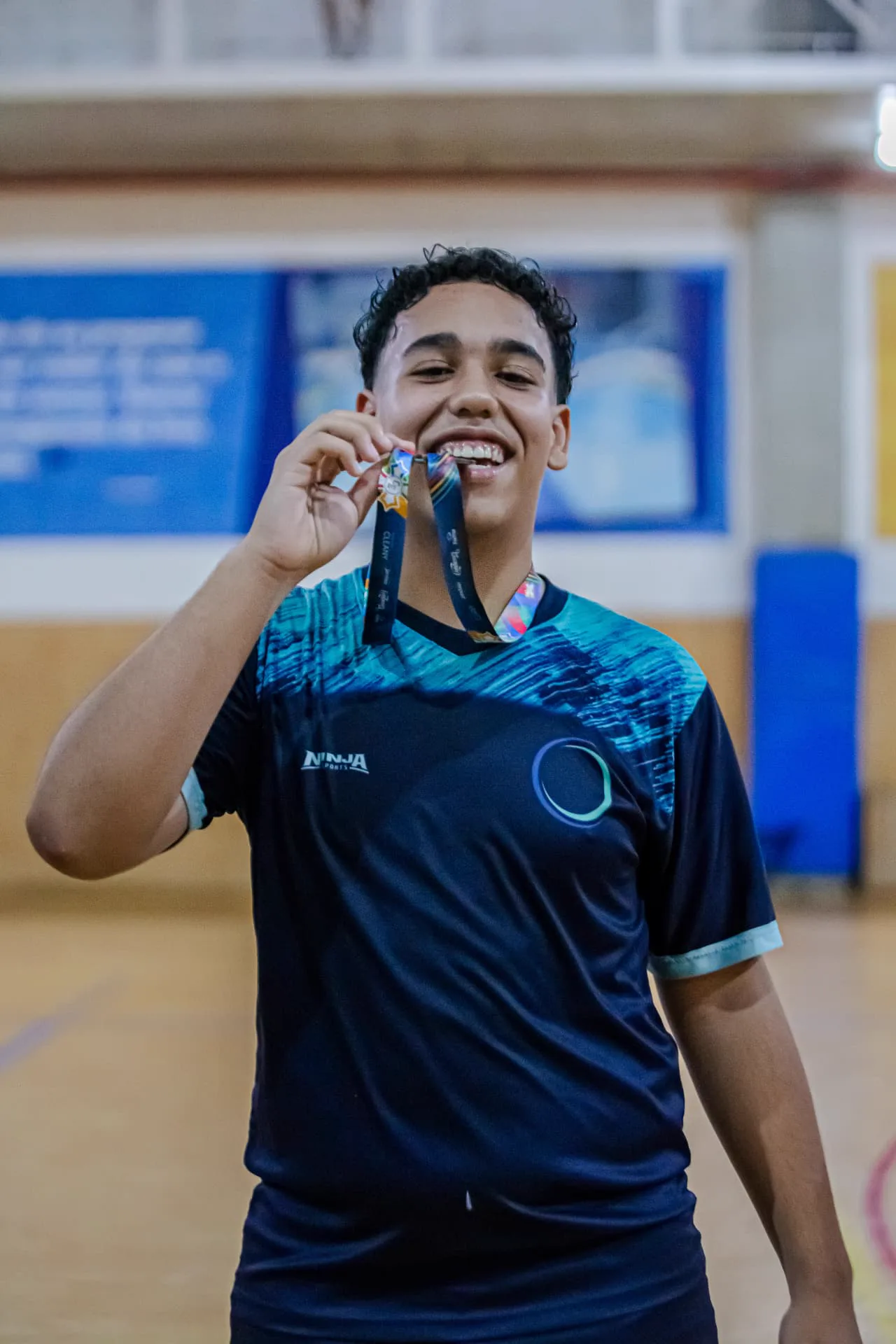 Atleta sorrindo e mordendo a medalha de premiação